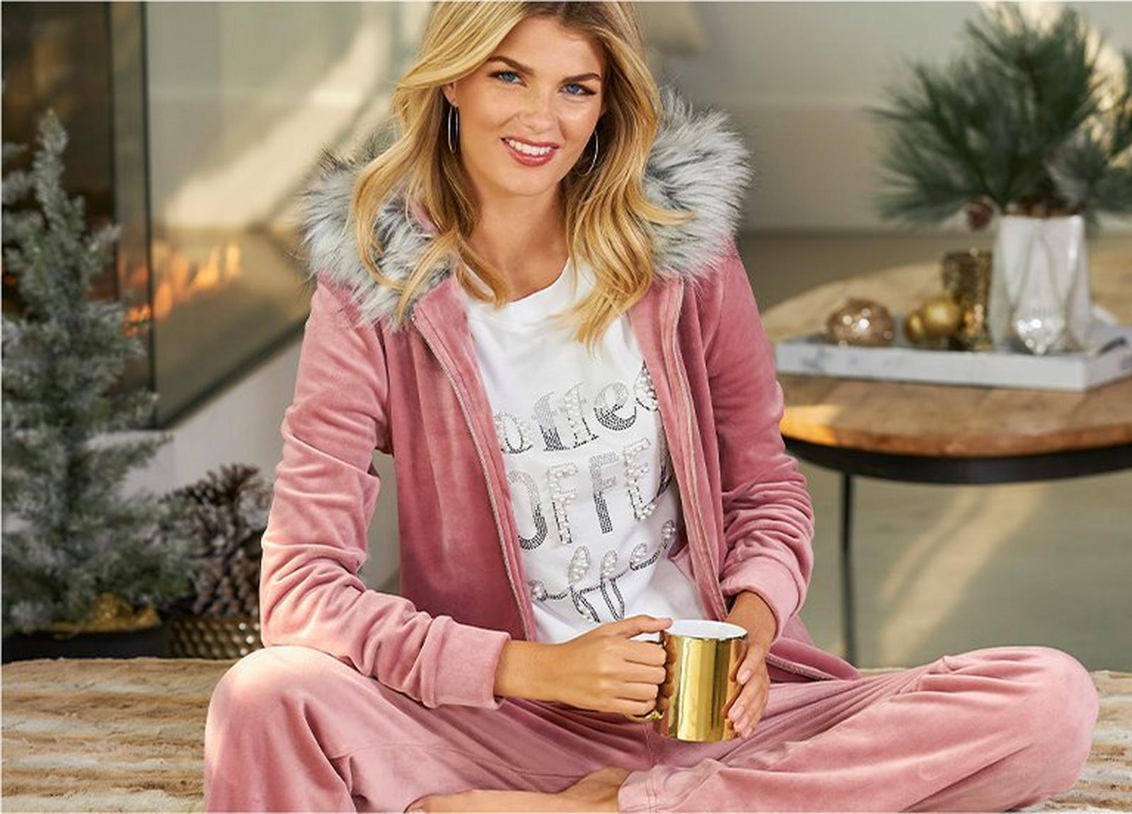model wearing a light pink velour two-piece set with gray faux-fur collar and a white pearl embellished graphic tee that says, 