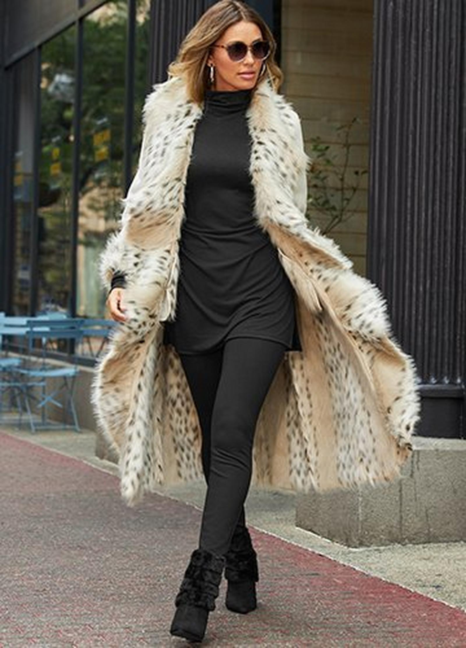 model wearing an off-white long coat with white leopard print faux-fur, black tunic top, black leggings, and black faux-fur booties.