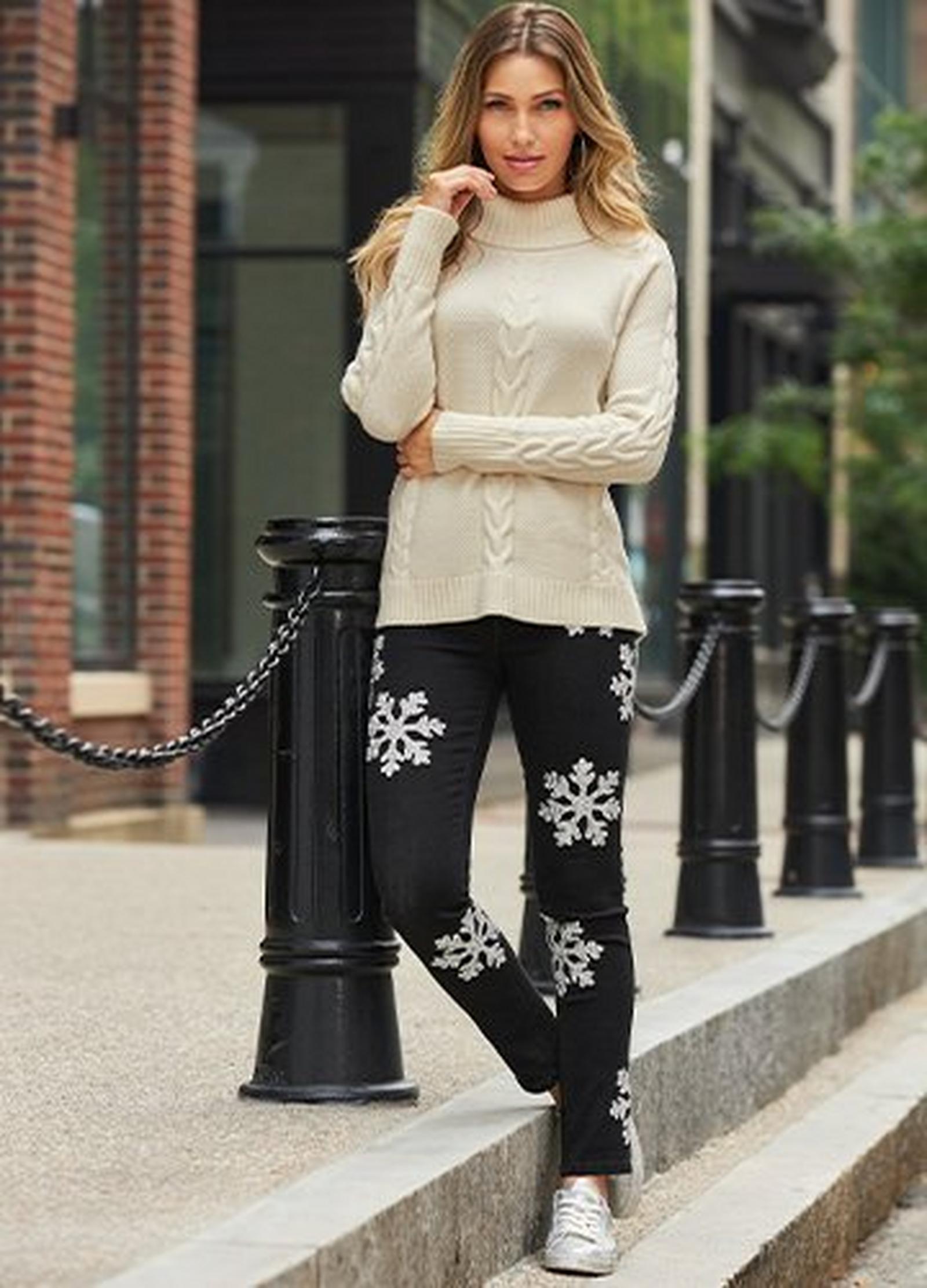 model wearing a white cable knit turtleneck sweater, black jeans with snowflake embellishment, and silver faux-shearling lined sneakers.