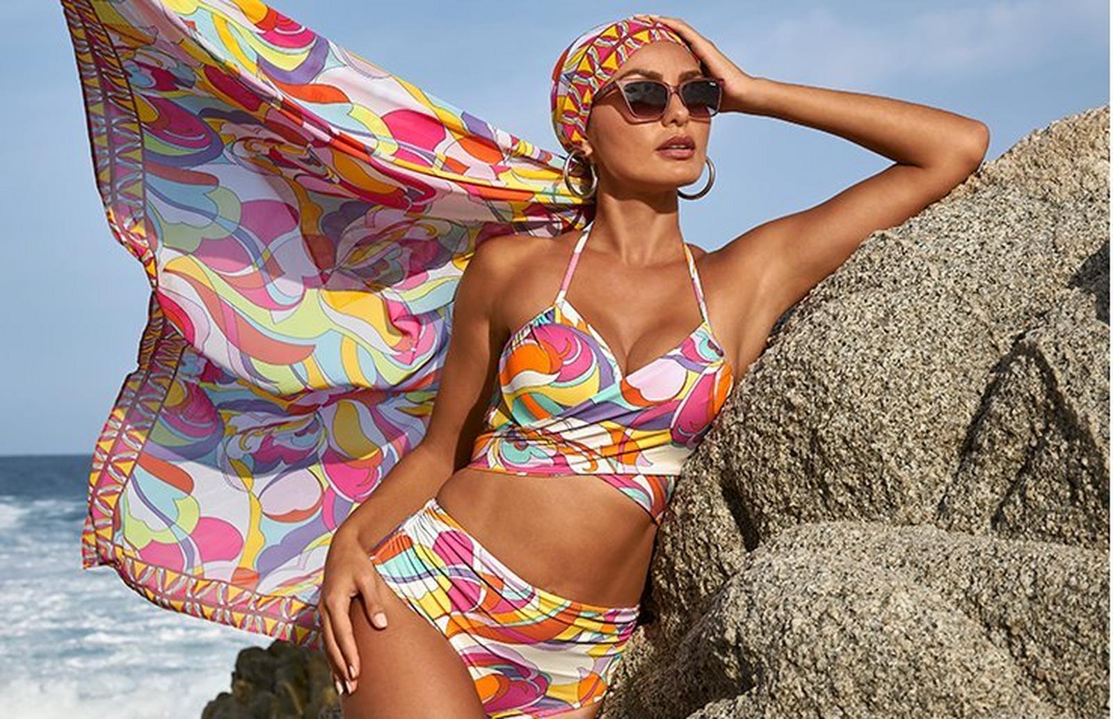 model wearing a sunset print bikini, matching headwrap, and sunglasses.