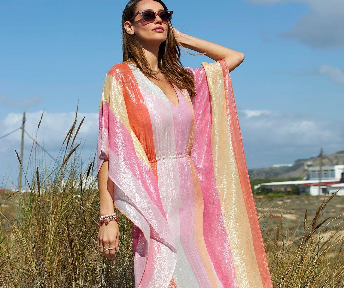 model wearing a multicolored sequin striped caftan dress and sunglasses.