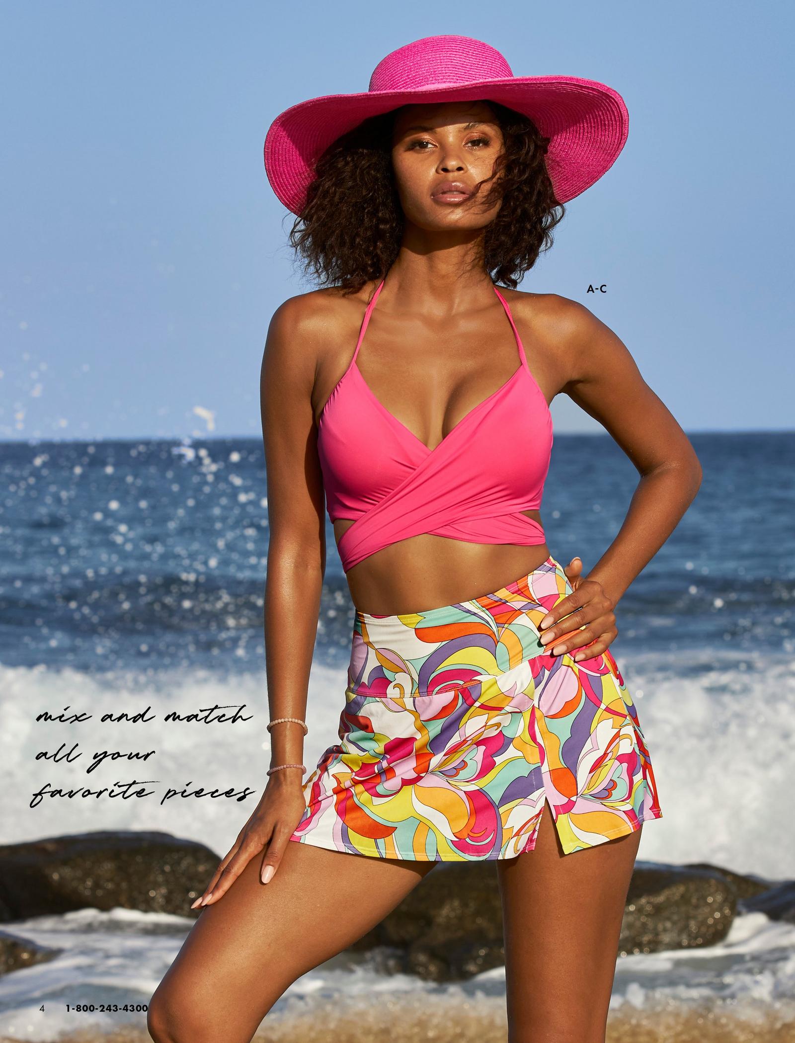 model wearing a pink bikini top, paisley print multicolored skirted bottoms, and pink wide brim hat.
