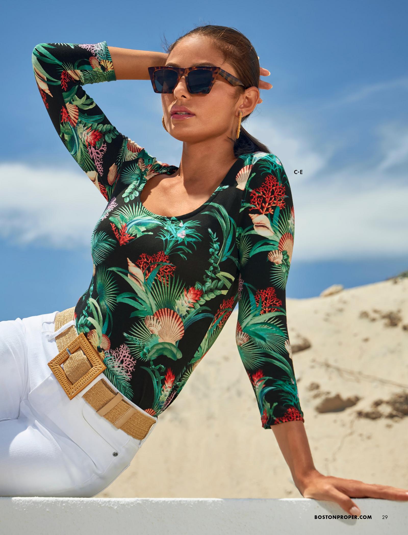 model wearing a sea life print scoop-neck three-quarter sleeve top, tan belt, white jeans, and sunglasses.