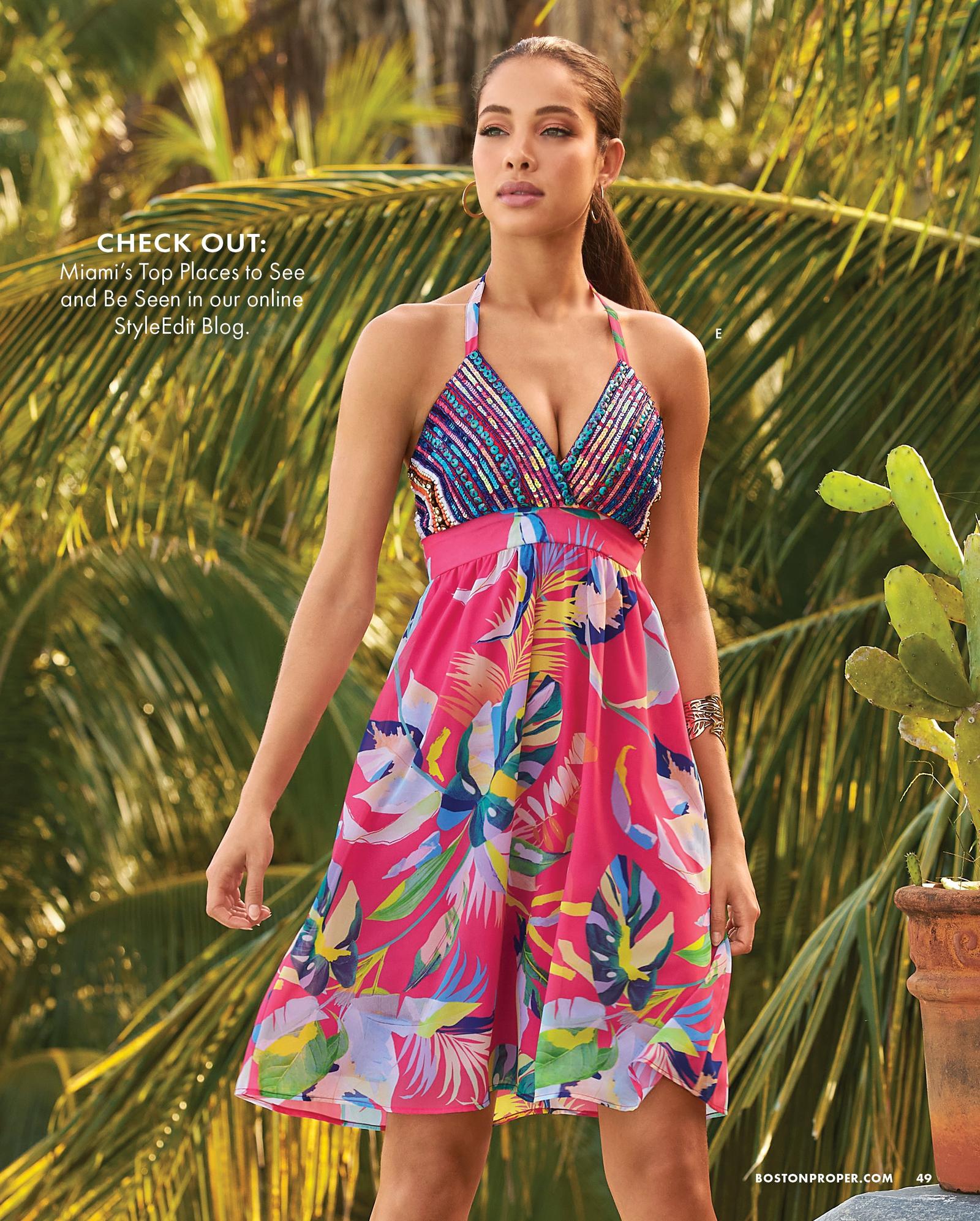 model wearing an embellished multicolored tropical print halter-neck dress.