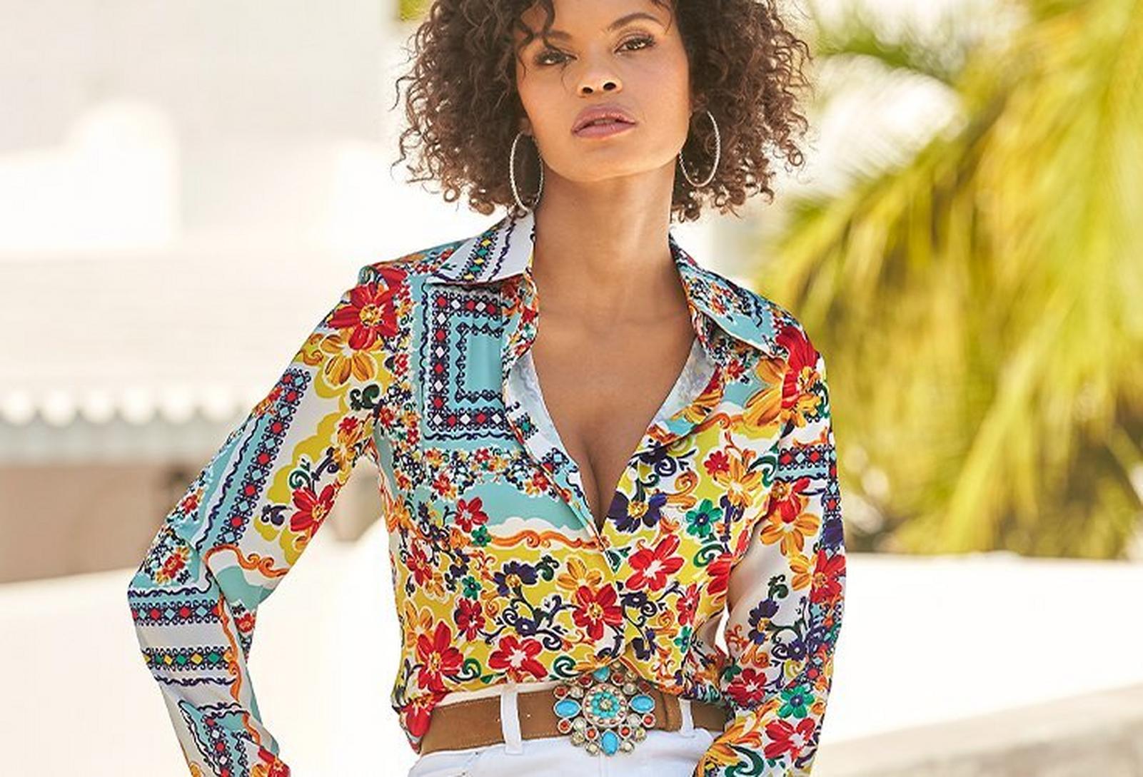 model wearing a scarf print multicolored long-sleeve button-up charmeuse blouse, stone embellished belt, and white jeans.