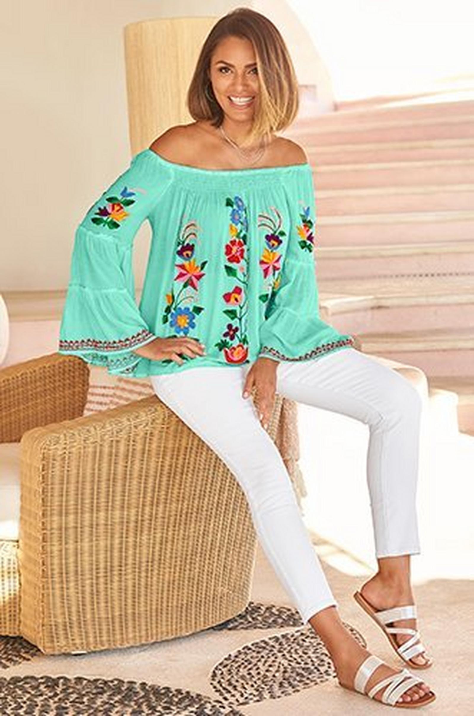 model wearing a mint off-the-shoulder floral embroidered flare-sleeve top, white jeans, and silver strappy sandals.