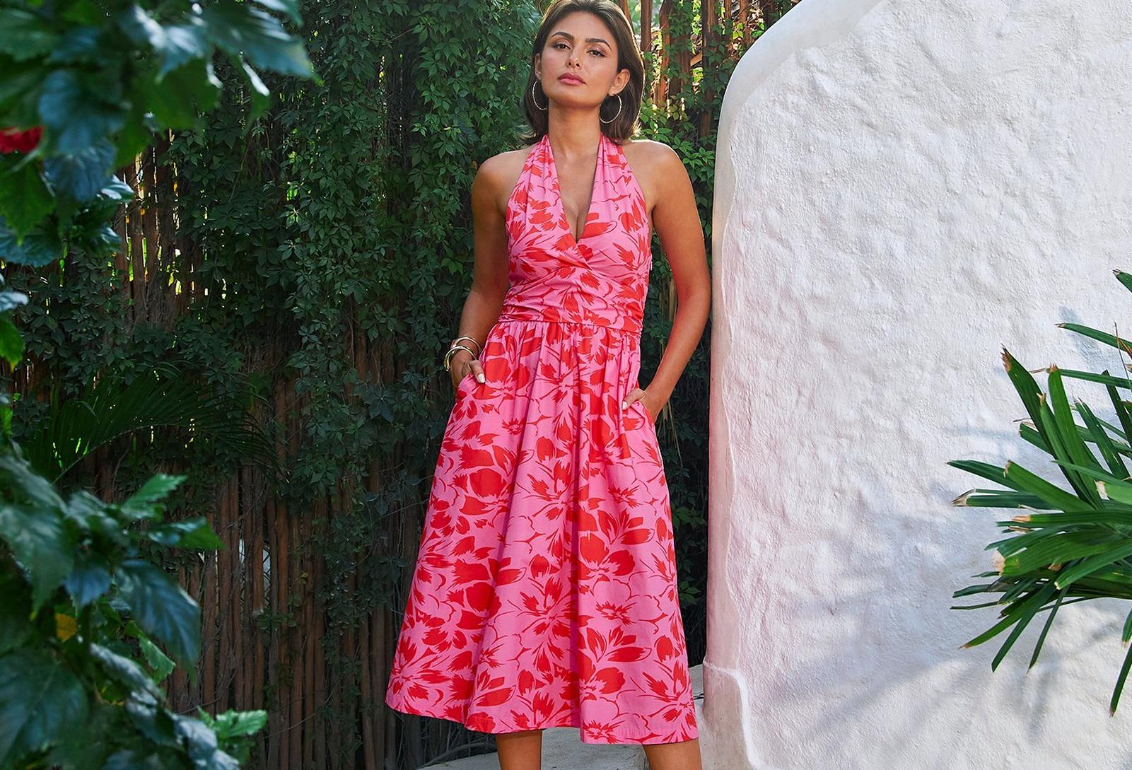model wearing a pink floral fit and flare halter neck midi dress.