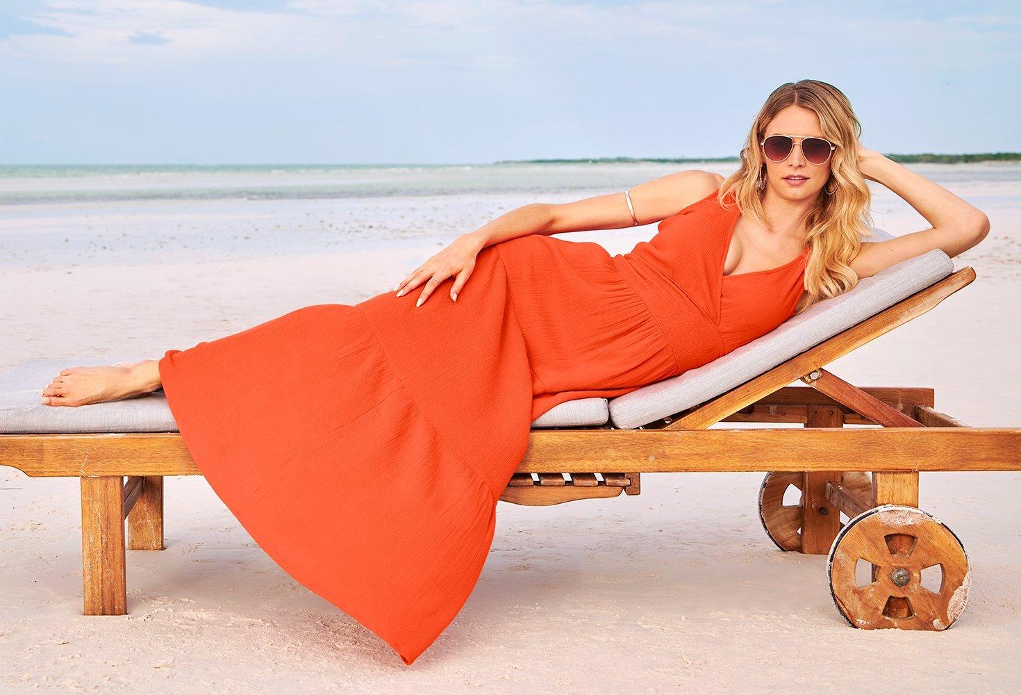 model wearing an orange v-neck sleeveless maxi dress and sunglasses.