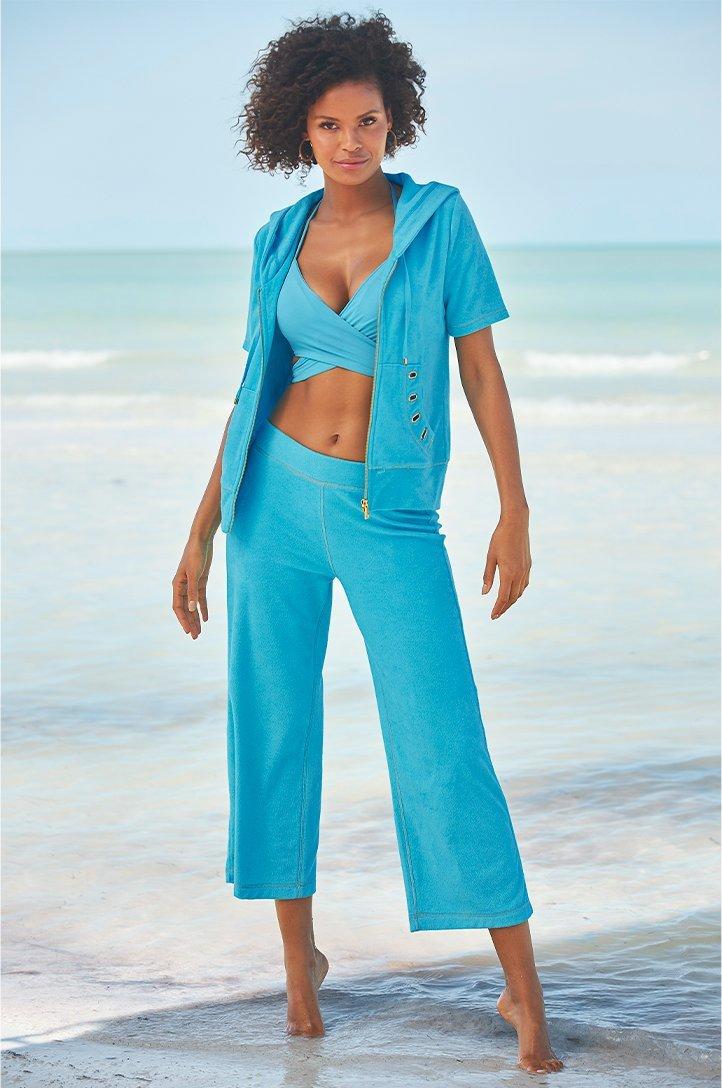 model wearing a blue terry two-piece jacket and cropped pant set and a blue bikini top.