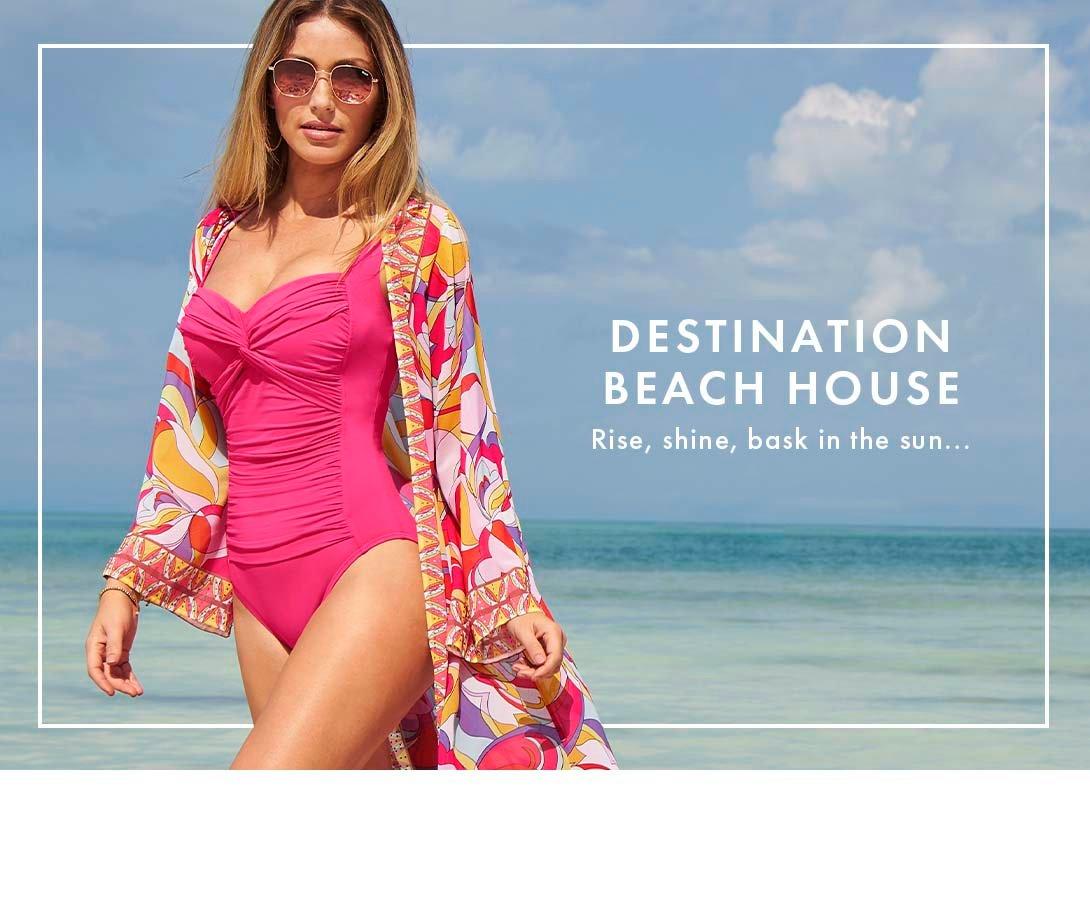 model wearing a multicolor paisley duster, pink one piece swimsuit, and sunglasses.
