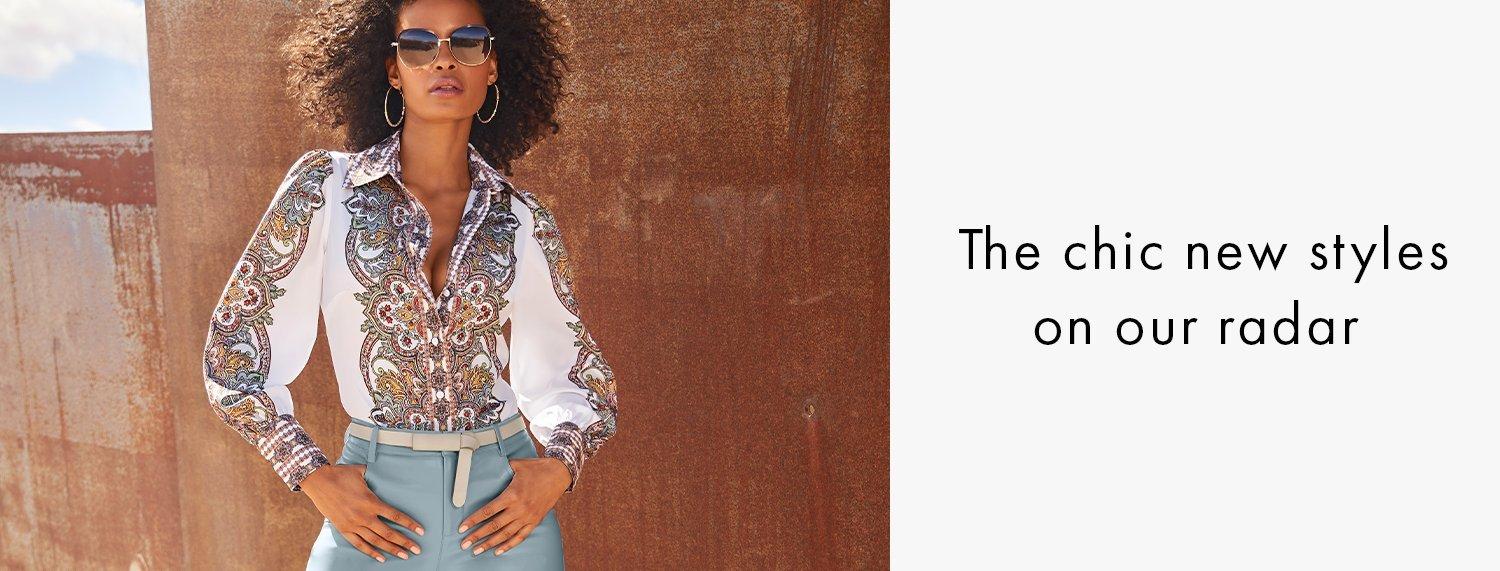 model wearing a paisley print balloon sleeve button-down top, thin light tan belt, light blue faux leather pants, and sunglasses.