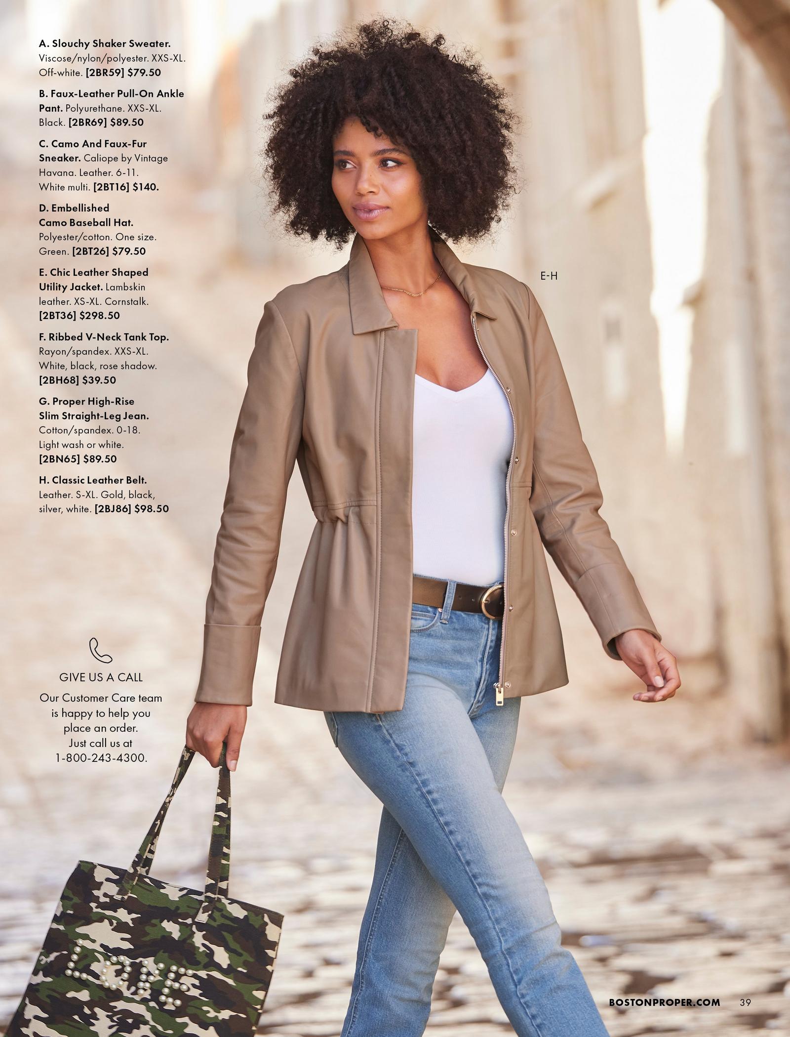 model wearing a tan leather shaped utility jacket, white v-neck top, black leather belt, jeans, and holding an embellished camo tote bag.