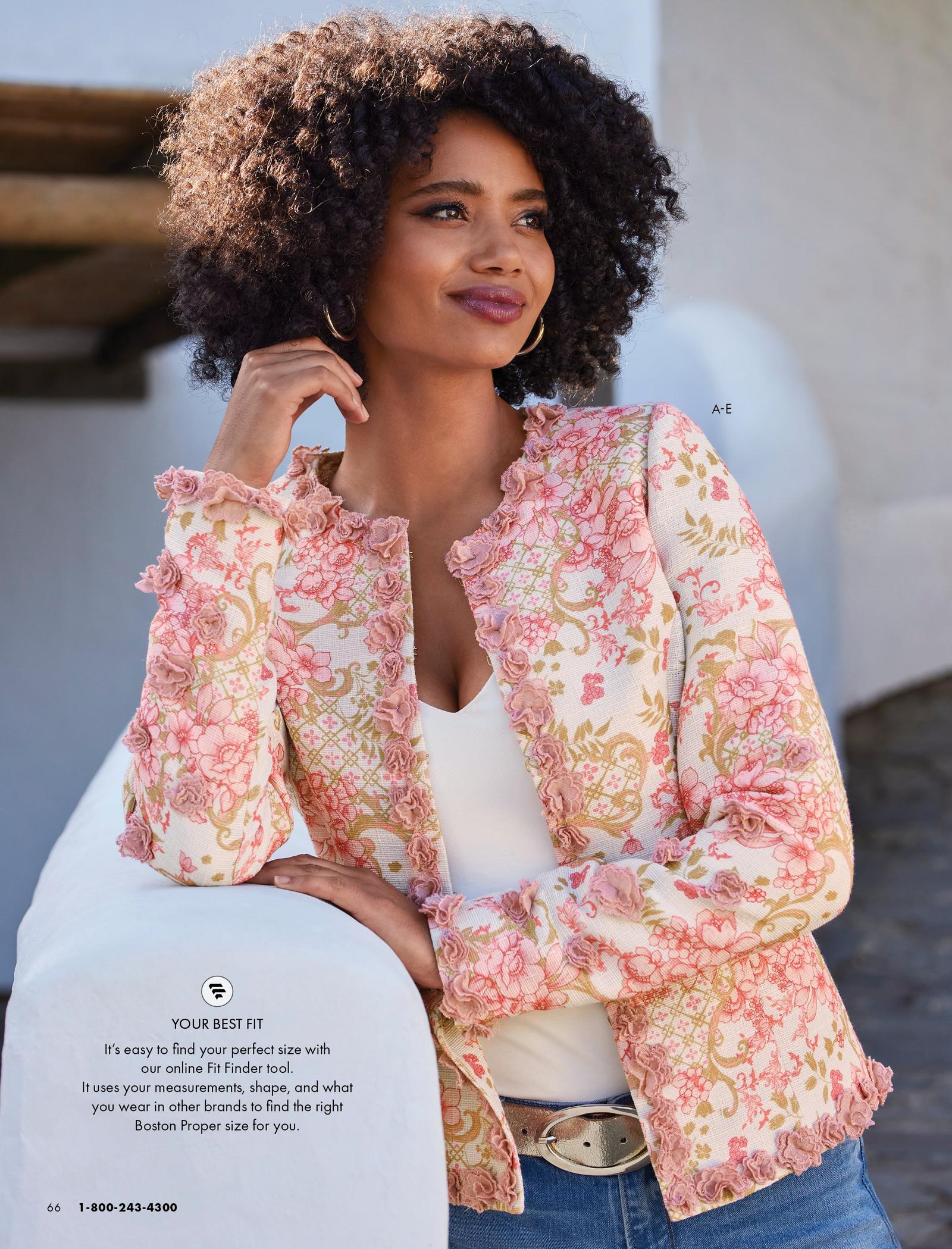 model wearing a pink 3d floral jacket, white v-neck top, gold leather belt, gold hoop earrings, and jeans.